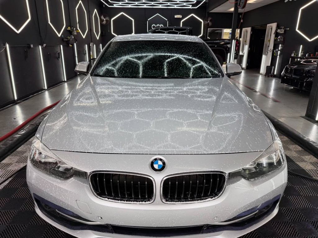 After detail — clean BMW with water beading on ceramic-coated hood in OCD studio