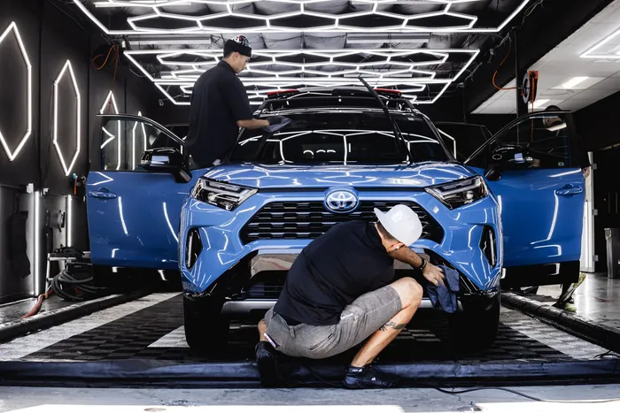 Two OCD technicians performing a full protection package under the studio's hexagon lighting